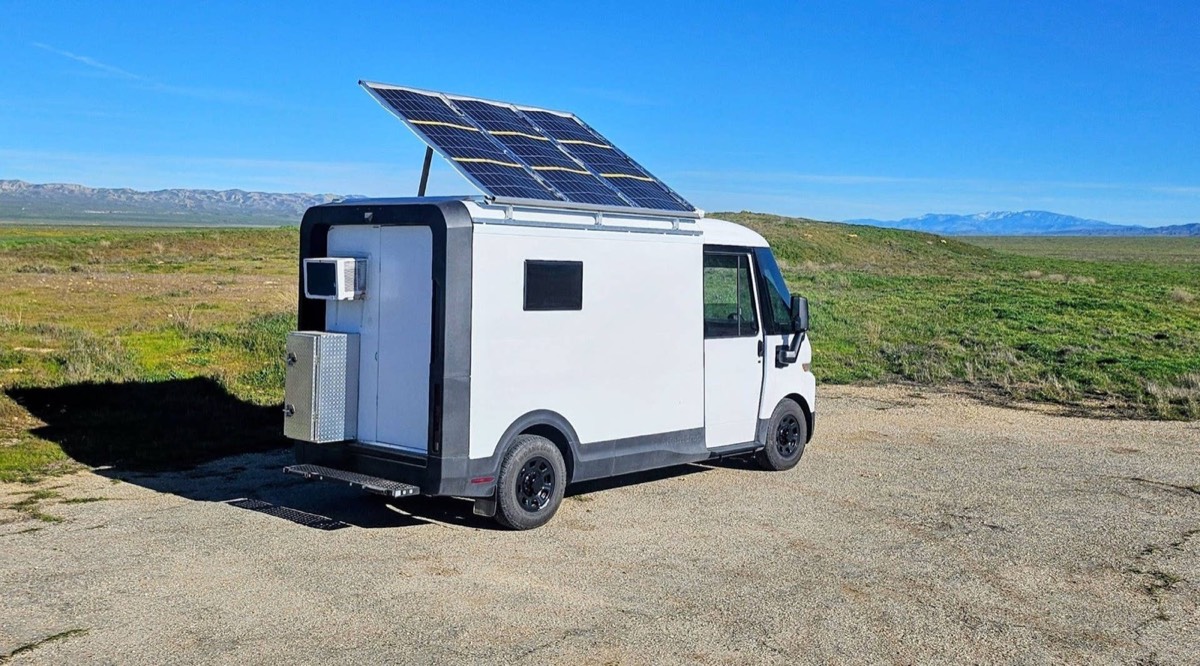 BrightDrop camper parked in open country with a tilting roof solar array raised
