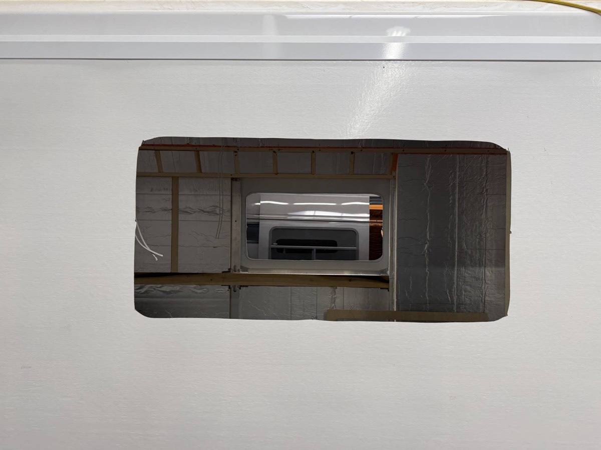 Rectangular window opening cut through a composite van side wall, seen from outside