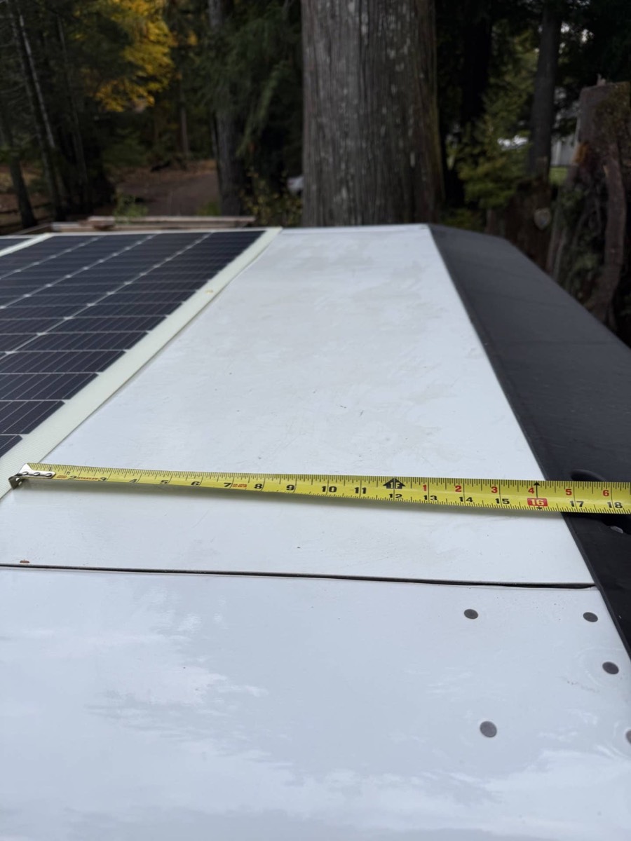 Tape measure stretched across a van roof between solar panels